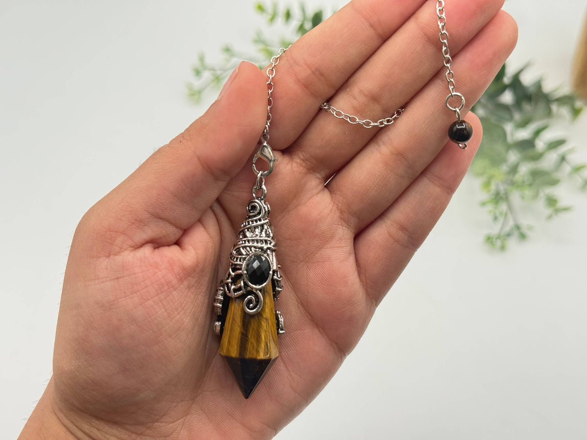 Hand holding a necklace with a unique pendant against a light background