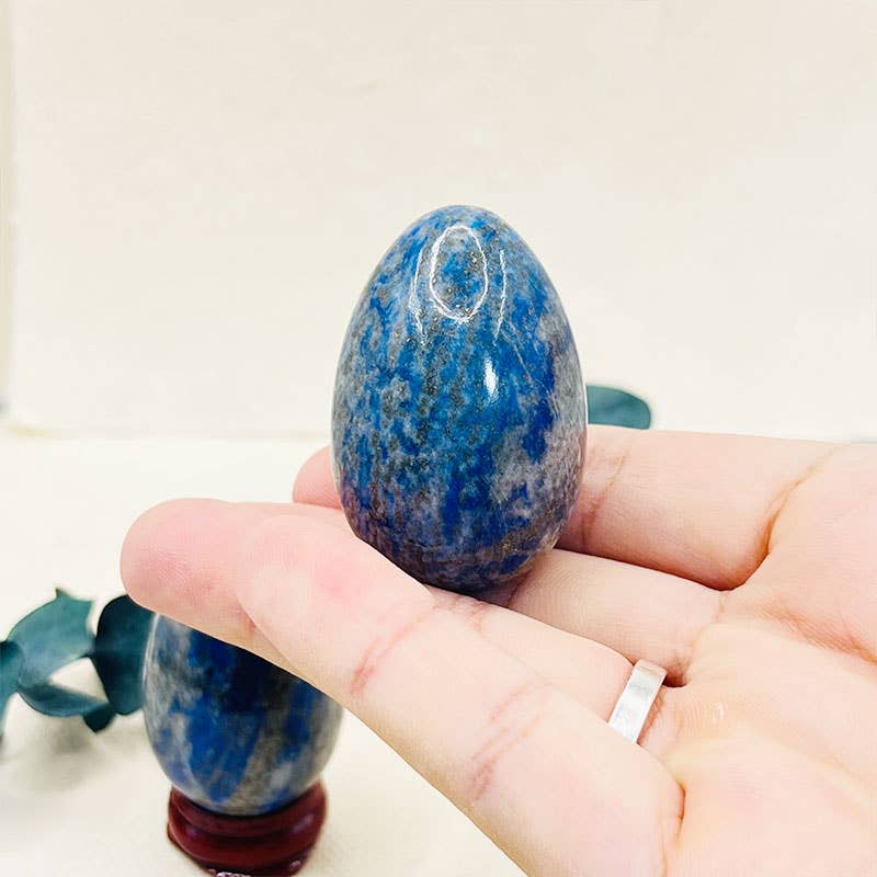 Hand holding a blue speckled stone with a plain background
