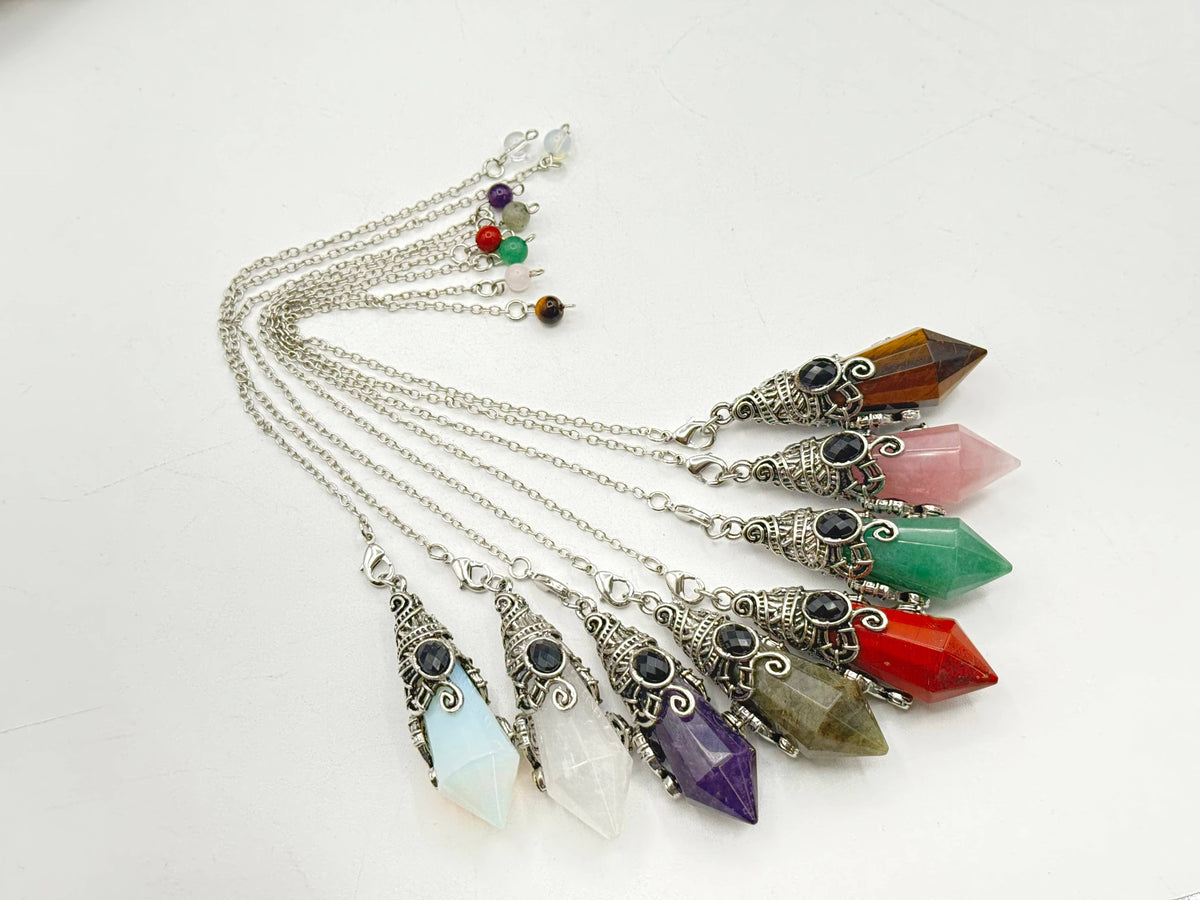 Set of colorful crystal pendants on silver chains against a white background