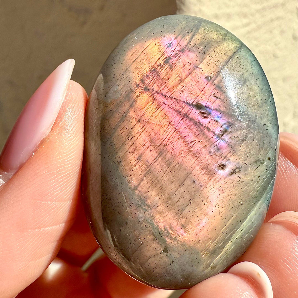 Person holding a rainbow-colored stone with a blurred background