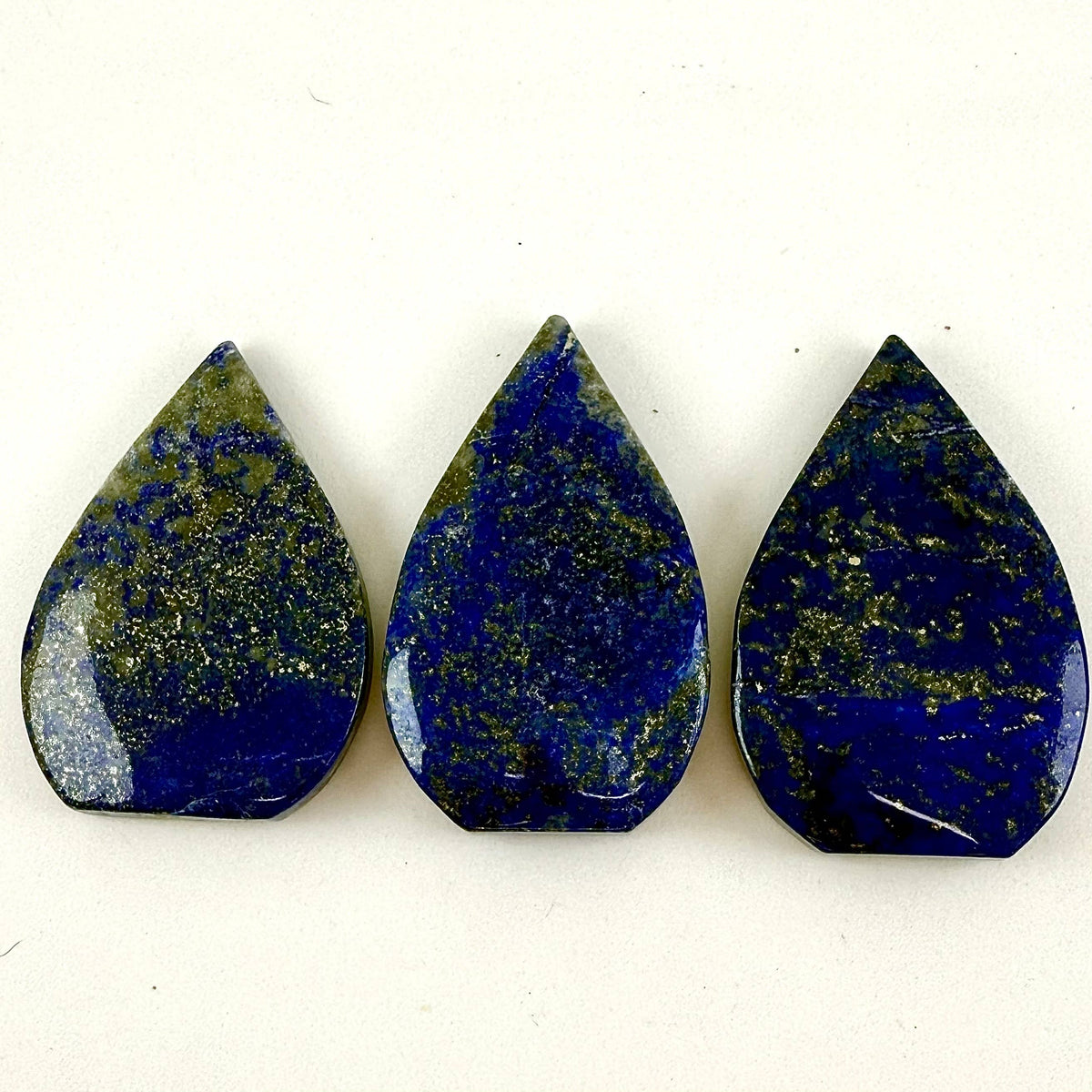 Three teardrop-shaped lapis lazuli stones on a white background