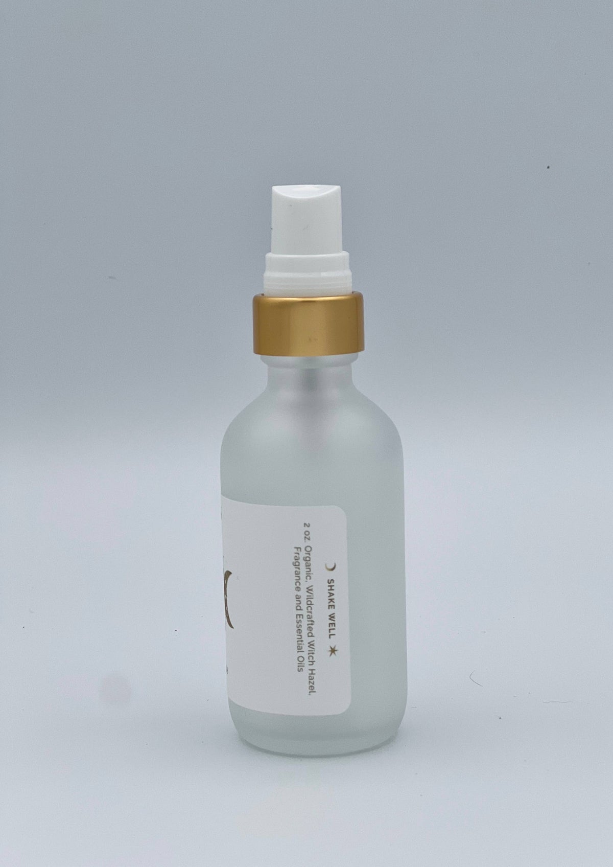 Clear bottle with gold cap and white label on a gray background