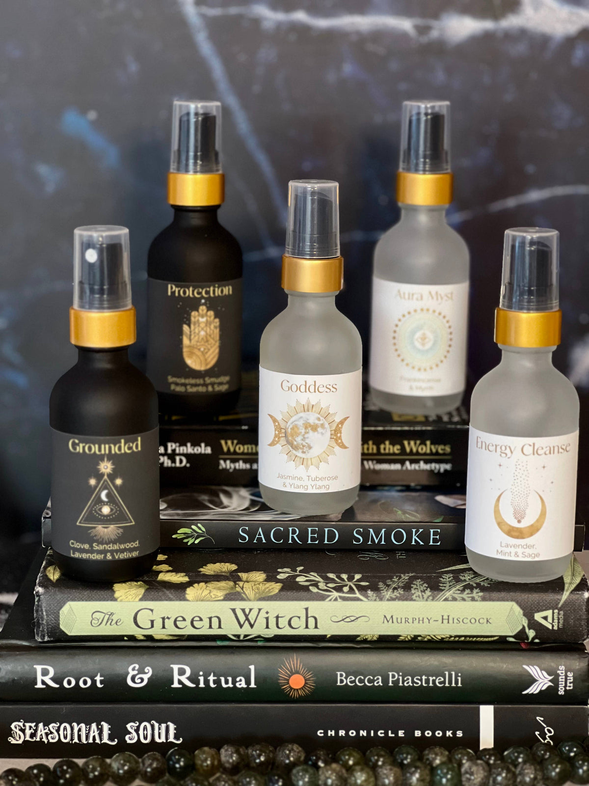 Collection of spiritual products including bottles and a book titled 'The Green Witch' on a dark background.