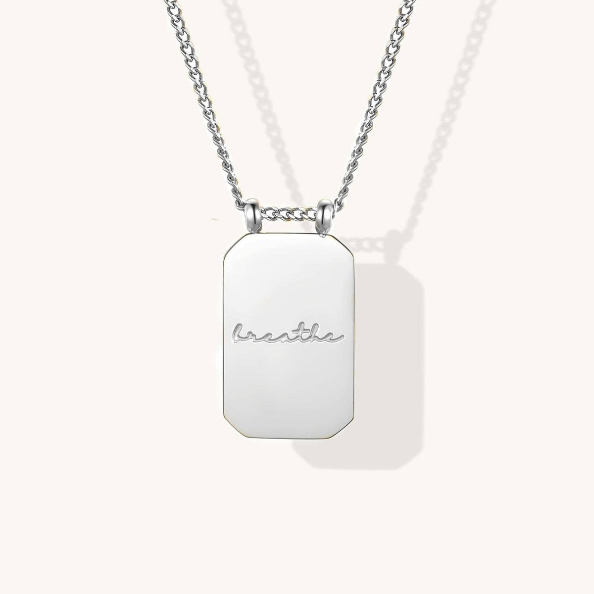 Silver necklace with a rectangular pendant on a white background