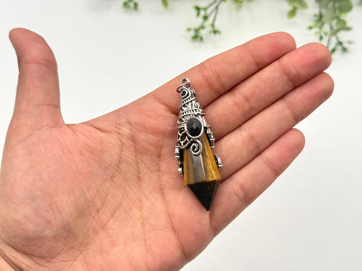 Hand holding a decorative pendant with a white background