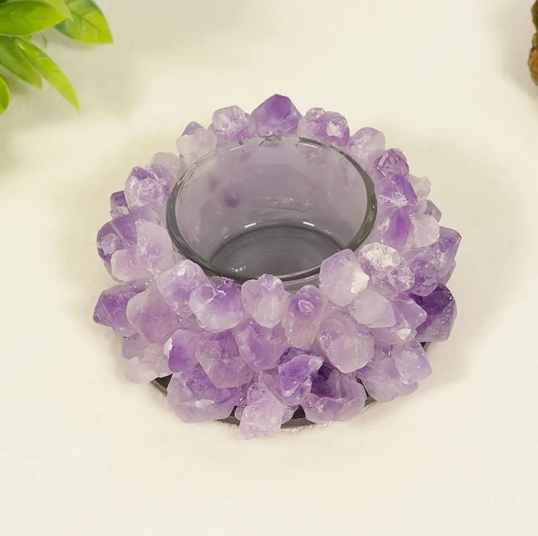 A candle holder made of hand-cut Amethyst crystals arranged in a lotus shape around a clear glass candle jar.