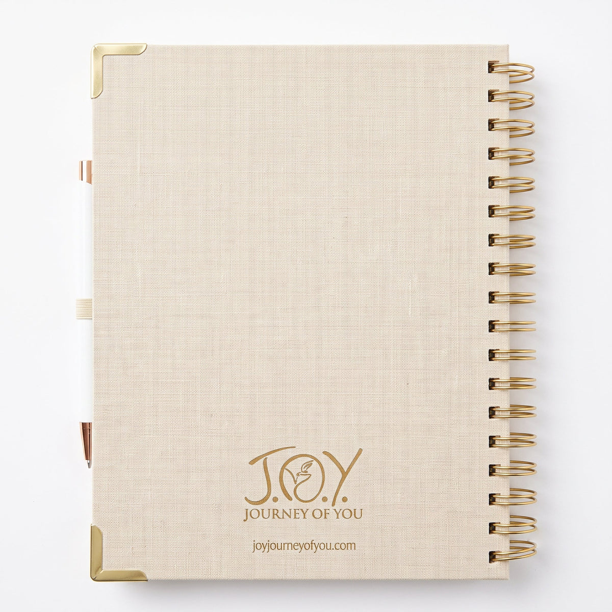 A beige linen-textured spiral notebook with gold corner protectors and a gold wire binding on the right side. The front cover features the gold foil-look branding 'JOY JOURNEY OF YOU' and the website 'joyjourneyofyou.