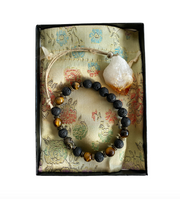 A gift box containing a bronze Buddha figure with tiger's eye beads and a citrine stone, all placed on a fabric with a floral pattern - JOY - Journey Of You - Spiritual, Holistic, Empowering