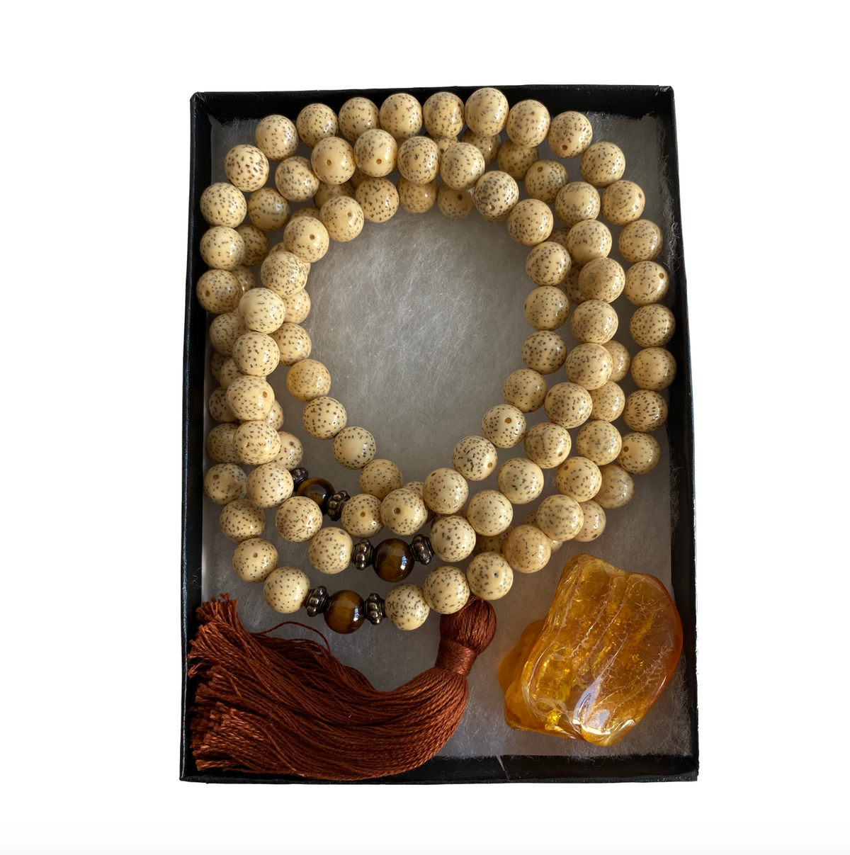 A mala with 8mm Lotus Seed Beads, featuring amber stone and tiger's eye, displayed in an open box with a red tassel - JOY - Journey Of You - Spiritual, Holistic, Empowering