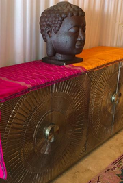 An orange and pink handmade altar cloth with gold threading, displayed in a room with a large bronze Buddha statue and decorative gold furnishings - JOY - Journey Of You - Spiritual, Holistic, Empowering