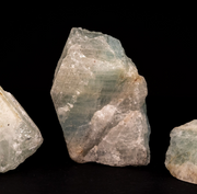 Three Raw Aquamarine Crystal of varying sizes displayed against a black background. 