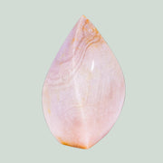 Teardrop-shaped pink stone with marbled pattern on a light green background