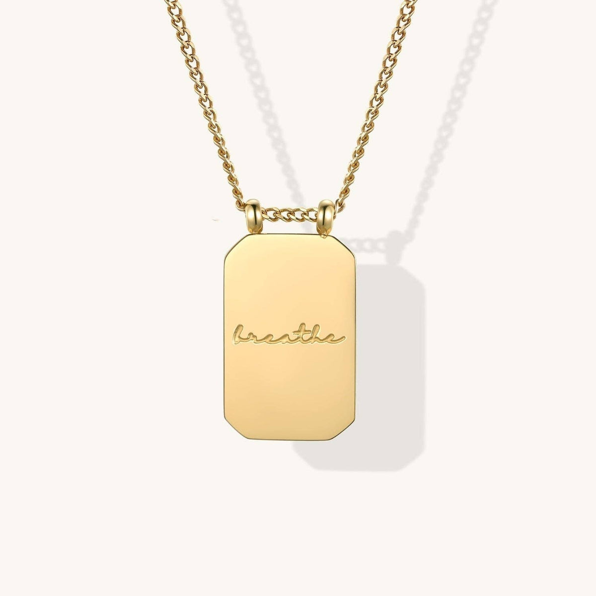 Gold necklace with a rectangular pendant on a white background
