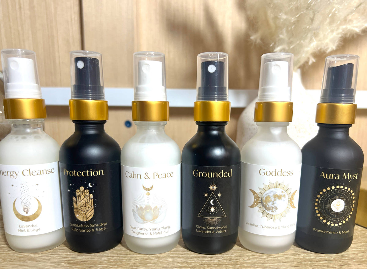 Set of six spray bottles with various labels on a wooden surface.
