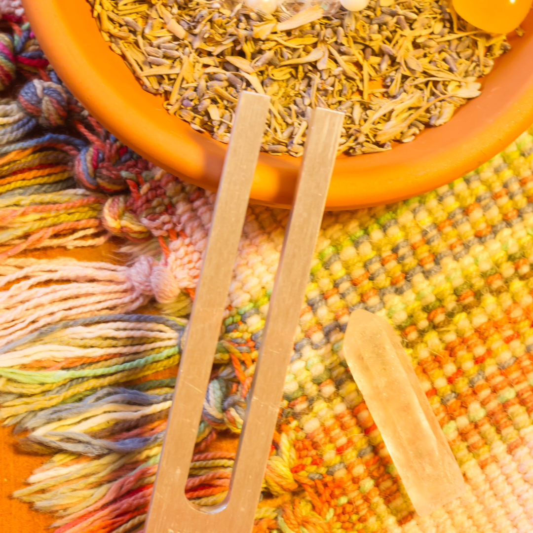 Wooden tea infusers in front of a bowl of dried herbs on a colorful fabric background