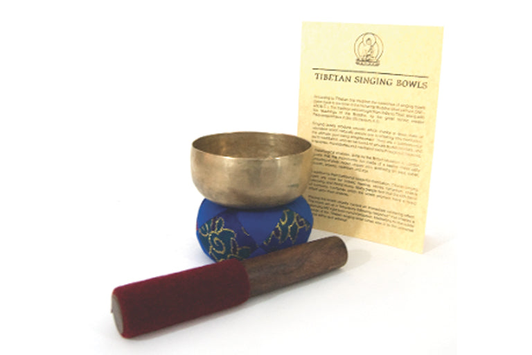 An antique singing bowl with a blue cushion and a red mallet, plus a paper with instructions, all laid out on a white surface - JOY - Journey Of You - Spiritual, Holistic, Empowering