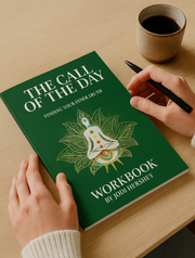Green workbook titled 'The Call of the Day' on a wooden table with a cup of coffee.